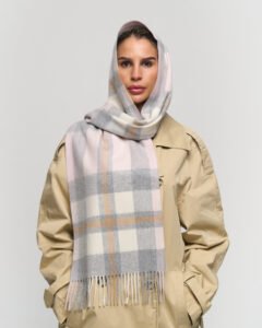 A premium navy and green tartan scarf draped over a luxury travel trunk, symbolising global reach and heritage.